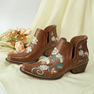 Close-up detail of vintage floral embroidery on brown Western-style square toe ankle boots