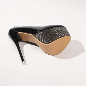 Detailansicht der Sohle schwarzer Lackleder-Plateau-Pumps mit glitzernden Strasssteinen.
