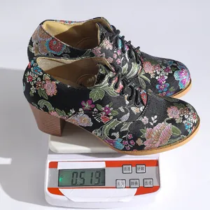 Detail shot showing the weight of vintage floral embroidered satin lace-up ankle boots.
