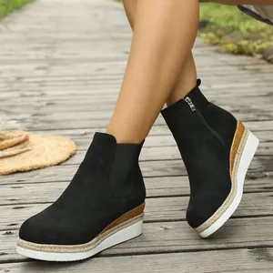 Nahaufnahme stilvoller schwarzer Keilabsatz-Stiefeletten für Damen auf Holzdeck