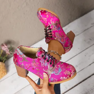 Close-up view of vintage fuchsia satin boots with intricate floral bird embroidery.