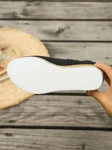 Detailansicht der weißen gerippten Sohle und des Jutebesatzes der schwarzen Keilstiefelette.