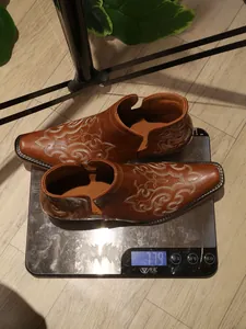 Close-up of brown embroidered Western cowboy boots on a scale showing 779g weight