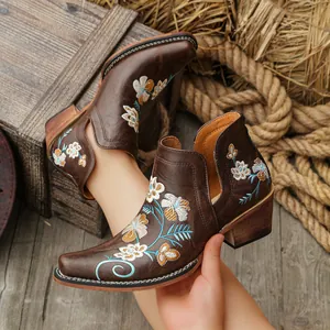 Detailed view of vintage brown Western ankle boots featuring vibrant floral embroidery