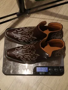 Detailed view of brown embroidered western ankle boots showing weight on a digital scale.