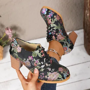 Detailed view of vintage black satin boots with colorful floral embroidery and block heel.