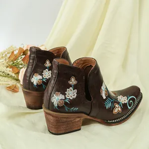 Detailed view of vintage brown western boots with intricate floral embroidery on the side.