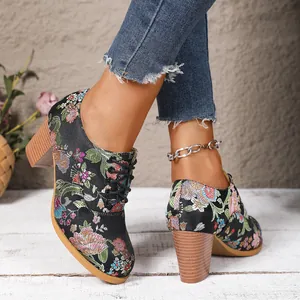 Detailed view of retro floral embroidered satin lace-up ankle boots with chunky high heels.