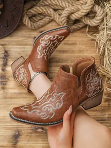 Detailed view of brown western ankle boots with white floral embroidery and side V-cut
