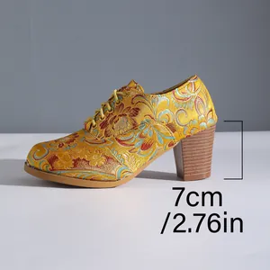Detail view of the 7cm block heel on vintage yellow satin embroidered floral lace-up pumps