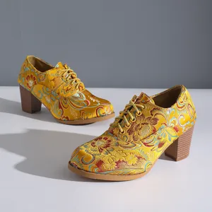 Close-up of yellow vintage floral embroidered satin high-heeled shoes with lace-up