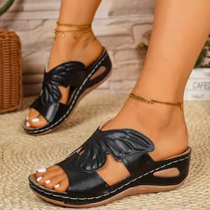 Detailed view of black wedge sandals featuring a butterfly wing cutout and white stitching