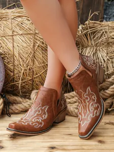 Close-up of vintage brown western boots featuring intricate white floral embroidery
