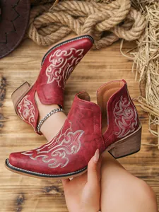 Detailed view of red Western ankle boots with white embroidery and V-cut sides.