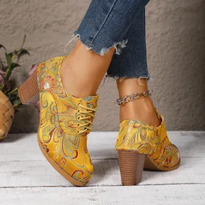 Close-up of yellow embroidered satin boots with intricate floral patterns and block heels.