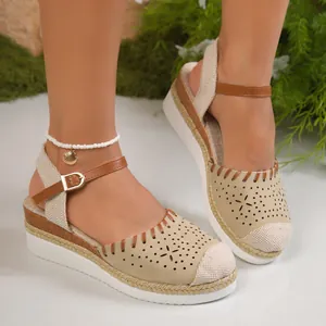 Dettaglio di sandali beige con zeppa traforati e cinturino regolabile marrone di tendenza