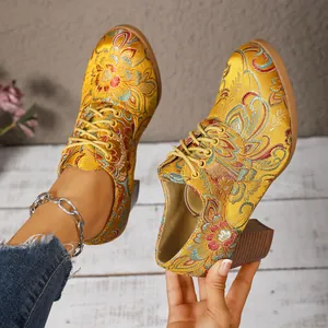 Detailed macro view of yellow satin embroidered block heel boots with floral pattern