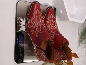 Close-up of vintage red cowboy ankle boots with white embroidery on a digital scale