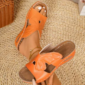 Close-up of vibrant orange wedge sandals featuring elegant butterfly motifs for summer.
