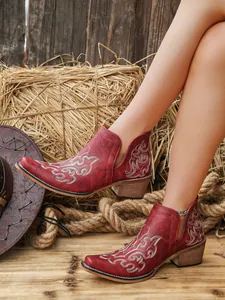 Close-up of red vintage women's ankle boots with elegant white embroidery details