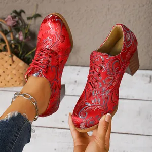 Close-up of retro red satin embroidered lace-up high heels with floral silver patterns