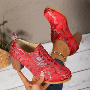Close-up of vintage red satin embroidered lace-up high heel boots with floral pattern