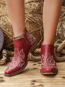 Macro view of red floral embroidered V-cut ankle boots with rustic chunky heel style