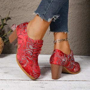 Close-up of vintage red satin ankle boots with elegant floral embroidery and thick heels.