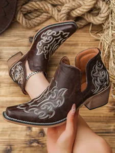 Detailed view of vintage brown cowboy ankle boots with white floral embroidery and V-cut.
