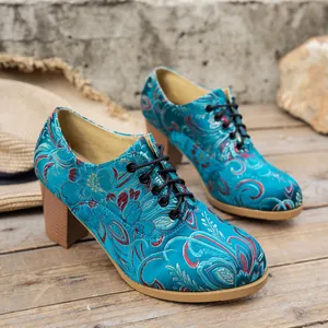 Close-up of turquoise vintage satin embroidered ankle boots with lace-up detail and chunky heel.