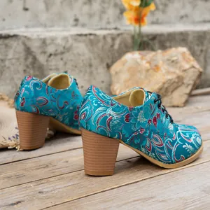 Detailed view of vintage teal satin floral embroidered lace-up boots with chunky brown heels.