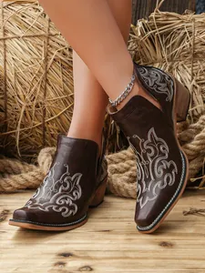 Detail of vintage brown ankle boots featuring white floral embroidery and a stylish V-cut