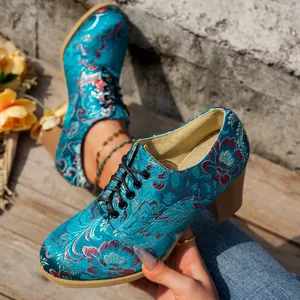 Close-up of vintage teal satin ankle boots with floral embroidery and block heel