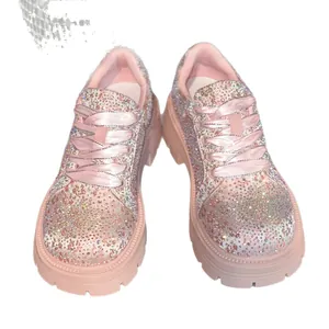 Close-up detail of pink rhinestone sneakers with platform soles and satin laces.