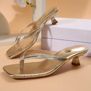 Detalle de sandalias de dedo doradas metalizadas con punta cuadrada y tacón bajo