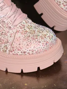 Macro view of pink platform shoes featuring sparkling rhinestones and thick sole details