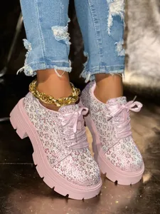 Detail view of pink platform sneakers with sparkling rhinestones and elegant ribbon laces.