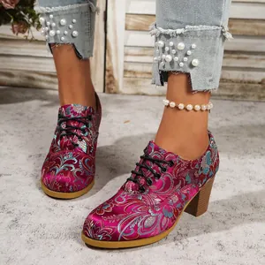 Close-up of vintage magenta satin boots with floral embroidery and chunky heel.