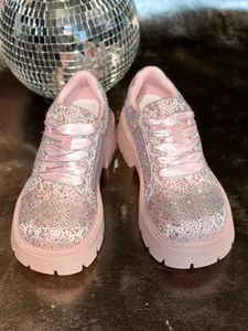 Detailed view of glamorous sparkling pink rhinestone platform sneakers with satin laces