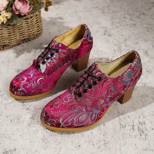 Detail shot of vintage floral embroidered satin ankle boots with block heels and laces.