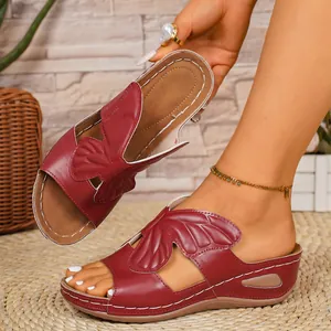 Close-up of red wedge sandals with butterfly wing design and white stitching peeptoe.