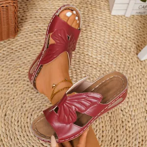 Detailed shot of burgundy wedge sandals featuring a beautiful butterfly design on top