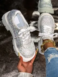 Detailed close-up of sparkly rhinestone-encrusted white platform sneakers with ribbon laces