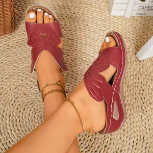 Detailed view of burgundy butterfly wing design on women's peep-toe wedge sandals