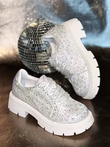 Close-up view of white chunky sneakers with colorful rhinestones and thick platform foam sole