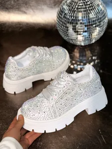 Close-up of sparkly rhinestone embellished white platform sneakers with chunky sole.