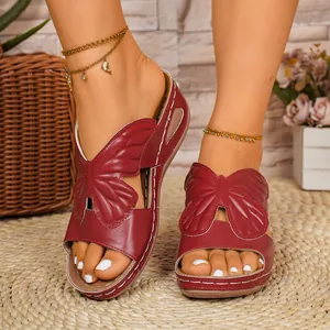 Close-up of stylish dark red women's slide sandals featuring a large butterfly design.