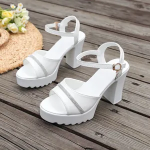 White platform sandals with rhinestone strap and chunky heel on a wooden deck