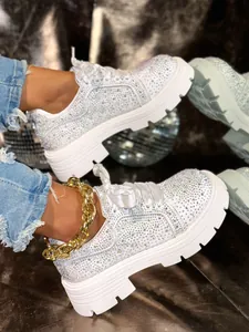 Close-up view of white rhinestone platform sneakers with thick sole and ribbon laces