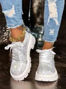 Close-up of sparkling white rhinestone sneakers with platform soles and ribbon laces